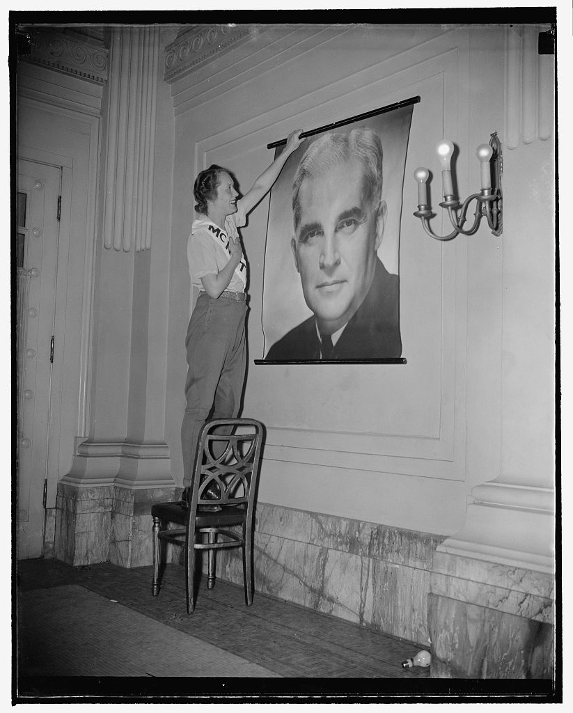 A woman named Mrs. O'Gridley, hanging up a photograph of handsome Paul, circa 1939-1940. This image became synonymous with McNutt's presidential campaign literature. Image courtesy of the Library of Congress.